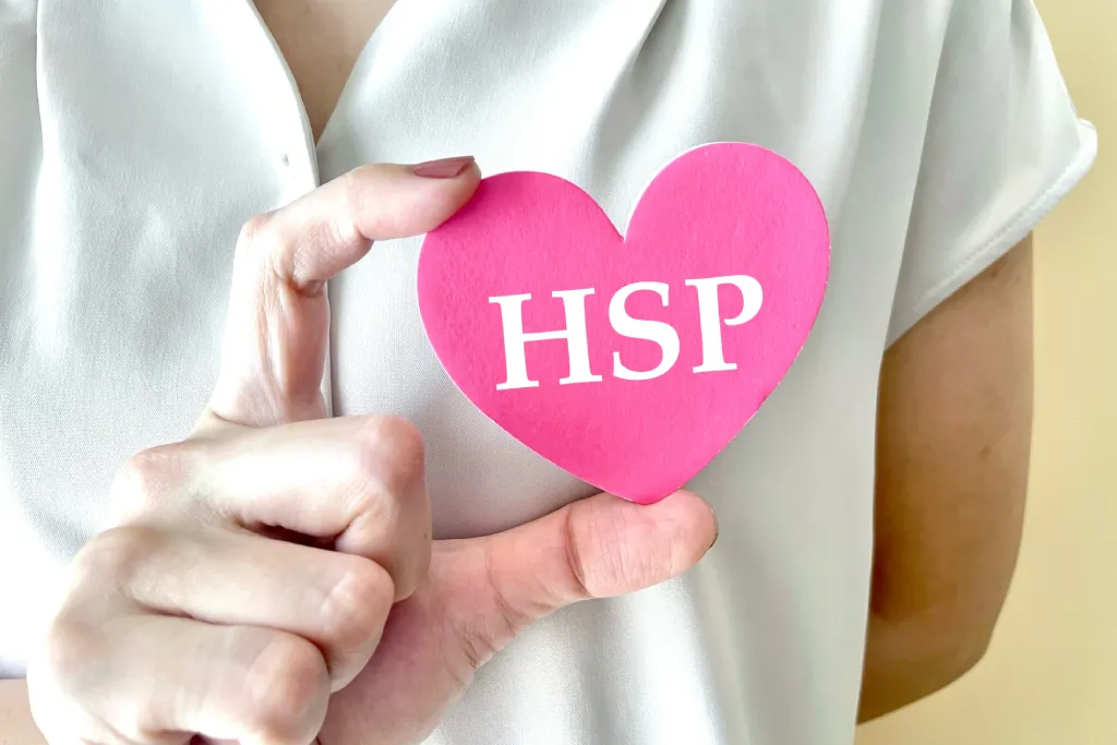 『HSP』と書かれたハート型の紙を持つ女性